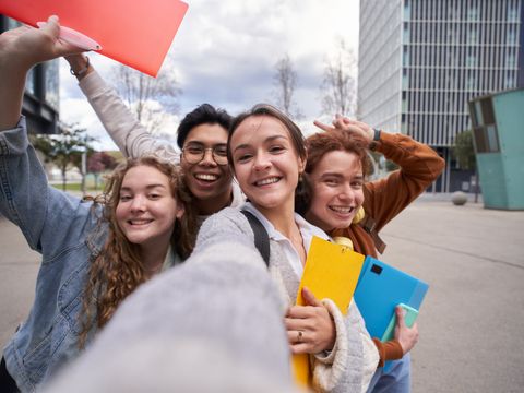 Vier lachende Studenten machen ein Selfie