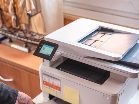 Eine Person legt Papier in einen Drucker ein