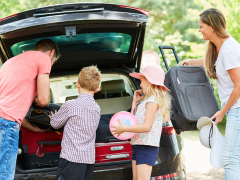 Familie mit Kindern packen Koffer in das Auto