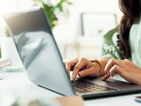 Hände einer Frau am Laptop; sie tippt am Schreibtisch