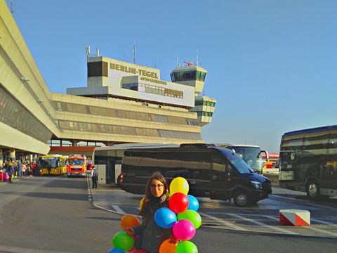 Eine junge Frau mit 50 Luftballons vor dem Flughafen Tegel in Berlin