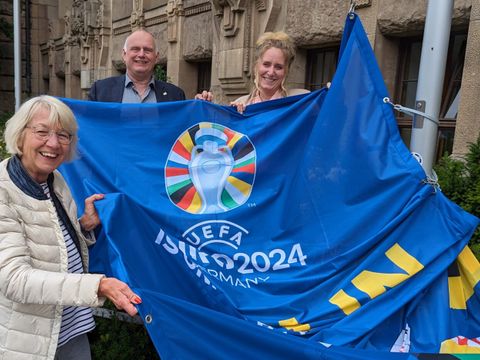 UEFA-Fahne gehisst: Bezirksbürgeremisterin Kirstin Bauch, der stellvertretende Bezirksbprgermeister Detlef Wagner und die Bezirksverordnete Dr. Felicitas Tesch mit der Fahne der UEFA EURO 2024 vor dem Rathaus Charlottenburg