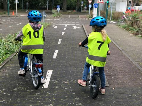 zwei Kinder sitzen auf Fahhrad und tragen Warnwesten