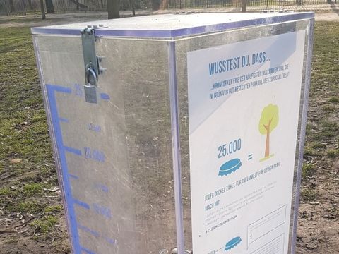 Ein durchsichtiger behälter in dem Kronkorken gesammelt werden können. Der behälter ist mit einigen Kronkorken gefüllt. Ein aufgedruckter Füllstandanzeiger zeigt die ungefäre Anzahl der gesammelten Kronkorken.