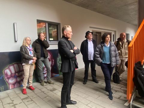 Der stellvertretende Bezirksbürgermeister, Oliver Nöll, und weitere Personen vor der Gedenktafel in der ehemaligen Gerhard-Hauptmann-Schule