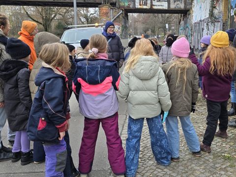 Bezirksstadträtin Annika Gerold (mi.) und die Umweltbildungskoordinatorin des Bezirksamts Katja Frenz (re.) besprechen mit den Schüler*innen der Fichtelgebirge-Grundschule die unterschiedlichen Wildblumen