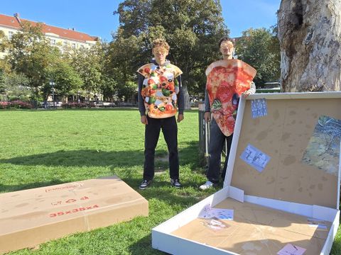 Jannis und Jakob präsentieren den größten Pizzakarton im Bezirk der stellvertretend für die Müllberge am Boxhagener Platz installiert wurde