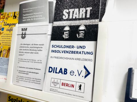 Mehrere Informationsbroschüren stehen nebeneinander in einem weißen Regal.