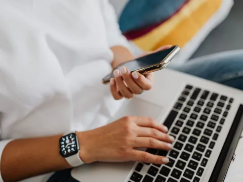 Person an Laptop und Smartphone