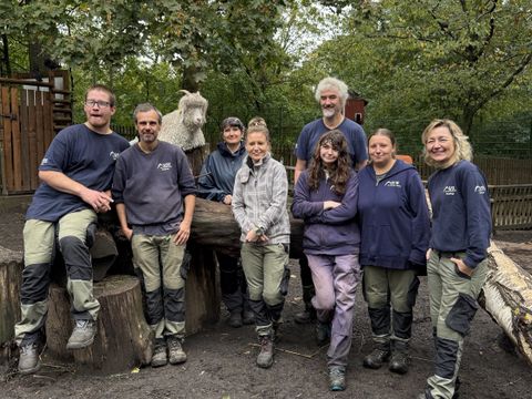 Zu sehen sind der Leiter der USE Tierpark Neukölln, Robert Seuntjens, sechs Mitarbeitende sowie die "Schichtwechslerin" Nicole Bieleke.
