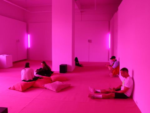 Ein pink beleuchteter Raum mit sitzenden Menschen