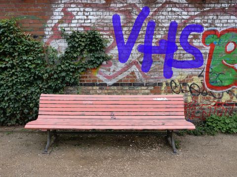 Eine rosa Bank steht vor einer Mauer mit Grafitti