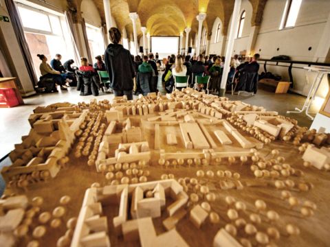 Stadtmodell mit sitzenden Personen dahinter und einem Präsentationsscreens
