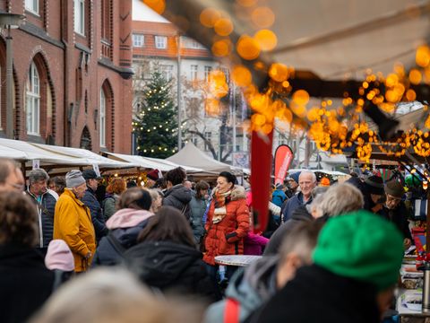 30. Lichtenberger Lichtermarkt, 30. November 2025: Blick durch die Gasse der Marktstände und Menschenmenge, viele Lichter
