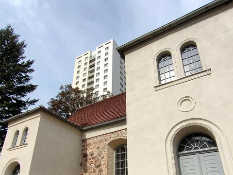 Alte Kirche mit hellen Mauern und Hochhaus im Hintergrund