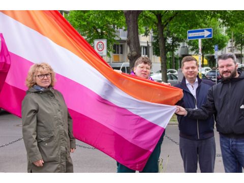 von links nach rechts: Sabine Pöhl, Diversity- und Queerbeauftragte; Anto Damm, LesLeFam e. V.; Bezirksbürgermeister Martin Schaefer und René Powilleit, LSU Berlin mit der Fahne zur lesbischen Sichtbarkeit. (Bild: Bezirksamt Lichtenberg)