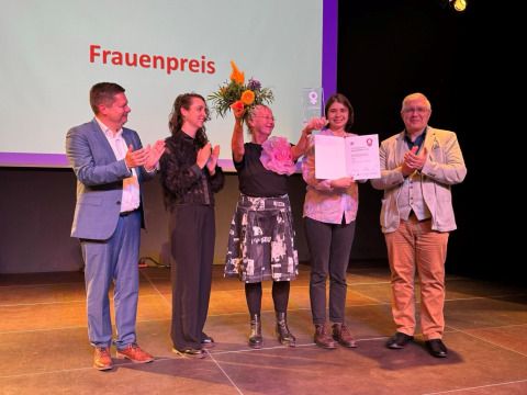 von links nach rechts: Bezirksbürgermeister Martin Schaefer, Gleichstellungsbeauftragte Eva Karpf, Mitarbeitende in dem Frauenhaus, in dem sich Rosi engagiert und Gregor Hoffmann, Vorsteher der BVV Lichtenberg, bei der Übergabe des Lichtenberger Frauenpreises 2025. (Bild: Bezirksamt Lichtenberg)