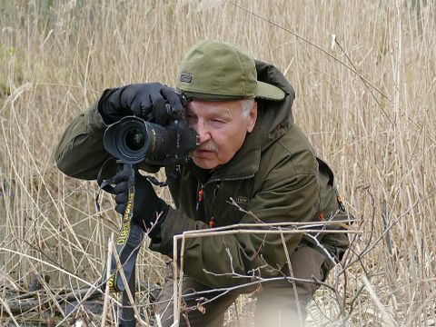 Naturfotograf Klaus Weber in Tarnkleidung mit Kamera und Stativ in der Natur
