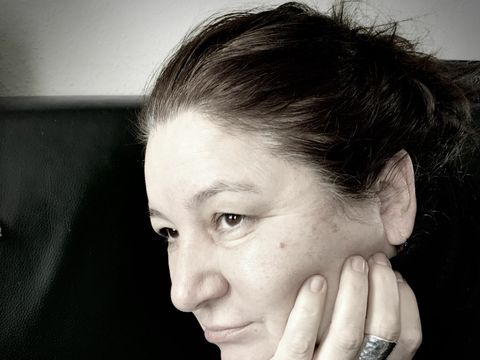 Ein Portrait von der Autorin Birgit Letze-Funke, sie sitzt das Kinn schwer in die linke Hand gestützt und schaut nach oben.