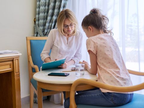 Woman teacher, therapist, social worker talking to preteen girl in office.