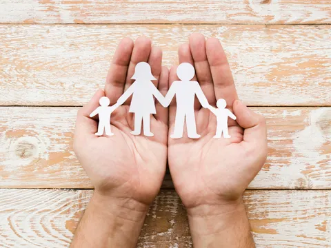 Hände die eine ausgeschnittene Papierfamilie halten
