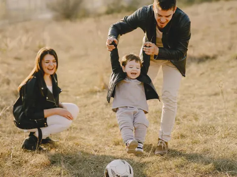 Mutter, Vater und Kind am Fußball spielen auf einem Feld