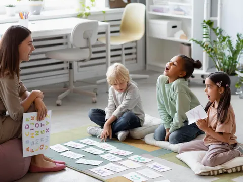 Frau betreut Kinder und lernt das Alphabet mit ihnen