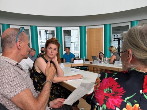 Teilnehmende des Klimarats sitzen an einer Tafel aus Tischen und unterhalten sich in Kleingruppen