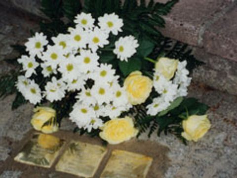 Foto von 3 Stolpersteinen mit Blumengebinde