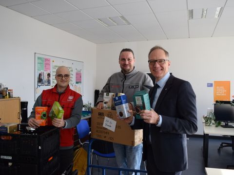 Der stellvertretende Bezirksbürgermeister Carsten Spallek übergibt gespendeten Kaffee aus der Kaffeewette an Dr. Jörge Bellin (Johanniter) und Joseph Salim (Caritas).