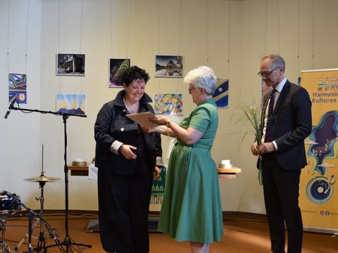 Fionnuala Devlin (l.) wird von Bezirksbürgermeisterin Stefanie Remlinger und Bezirksstadtrat Carsten Spallek mit dem Ehrenamtspreis 2026 ausgezeichnet.