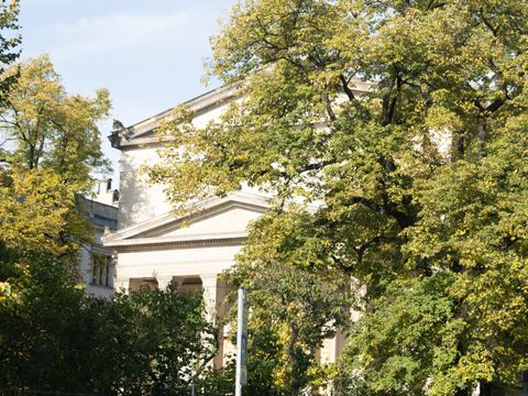 Ein Kirchengebäude hinter herbstlich gefärbten Bäumen