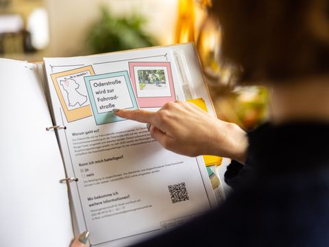 Hand zeigt auf Blatt mit Informationen zu einer Beteiligung