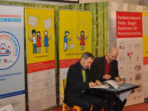 Bezirksbürgermeister Sören Benn und Dominik Bär, Geschäftsführer des Vereins Kinderfreundliche Kommunen e.V., bei der Unterzeichnung