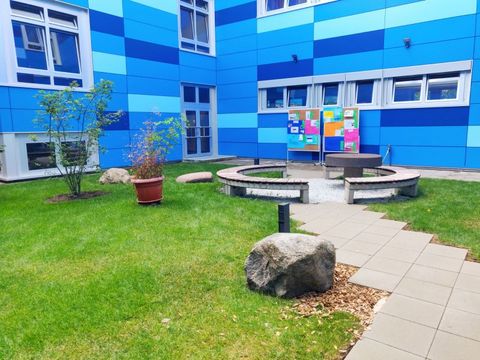 Neu gestaltetes Atrium vor der energetisch frischsanierten blauen Schulfassade (Bild: BA Reinickendorf)