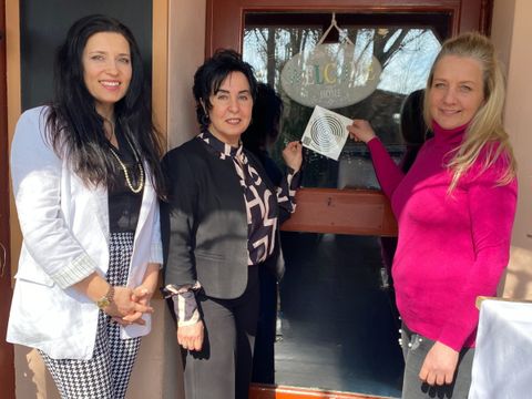 Einsamkeitsbeauftragte Katharina Schulz, Bürgermeisterin Demirbüken-Wegner und Geschäftsführerin vom Landhaus Schupke Melanie Niemann befestigen den Einsamkeitssticker an der Tür.