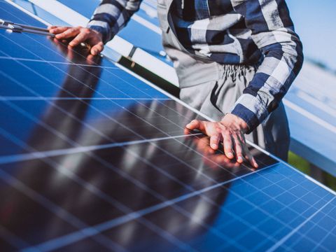 Das BIld zeigt einen Mann, der ein PV-Modul installiert.