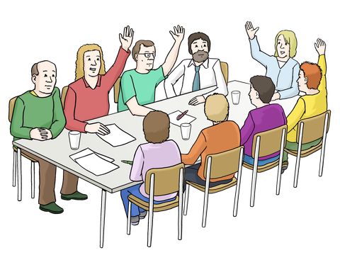 Menschen sitzen an einem Tisch mit Dokumenten und einige heben die Hand