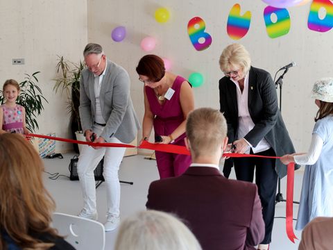 Mario Bade (SenBJF), Irina Wissmann (Schulleiterin) und Cerstin Richter-Kotowski (Bezirksstadträtin) zerschneiden das Band zur symbolischen Eröffnung der Holz-MEB. (Bild: Bezirksamt Steglitz-Zehlendorf)
