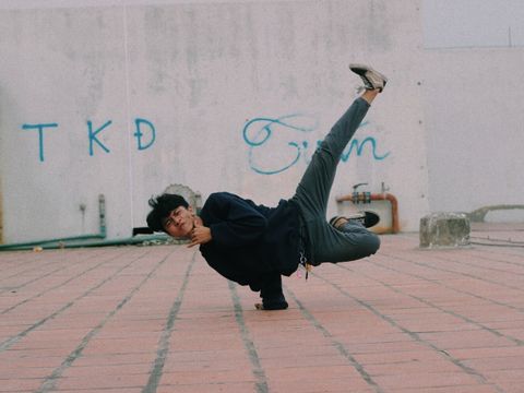 Beispielfoto: Ein Jugendlicher macht eine Breakdance-Pose, bei der er sich mit einem Arm vom Boden abstützt und seine Beine akrobatisch in der Luft hält.