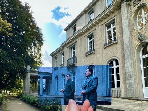 Haus der Wannsee-Konferenz – Die Wannseekonferenz: Hand hält Foto einer Filmszene mit zwei Schauspielern auf der Terrasse der Villa