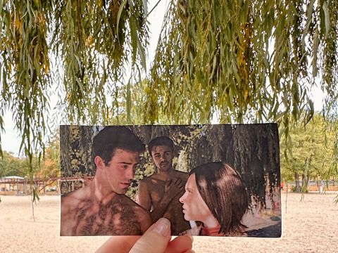 Strandbad Wannsee - Unorthodox: Hand hält Foto einer Filmszene mit drei Personen (v.l.n.r.: Aaron Altaras, Langston Uibel & Shira Haas) in die passende Kulisse des Drehorts