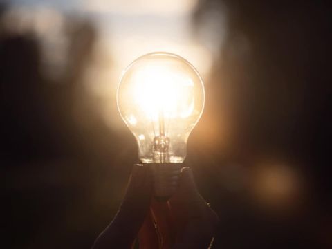leuchtende Glühlampe in der Hand in dunklem Raum
