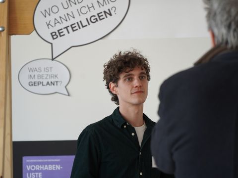 Zwei Personen im Gespräch vor einer Ausstellungswand