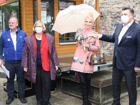 Von links nach rechts: Nachtbürgermeister Bastian Finke, Bezirksbürgermeisterin Angelika Schöttler, Schauspielerin Desiree Nick und Innensenator Andreas Geisel stehen zusammen vor dem Infopunkt Regenbogenkiez. (Bild: Bezirksamt Tempelhof-Schöneberg)