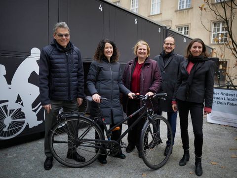 Von links nach rechts: Jörn Oltmann (Bezirksbürgermeister Tempelhof-Schöneberg), Bettina Jarasch (Senatorin für Umwelt, Mobilität, Verbraucher- und Klimaschutz), Angelika Schöttler (Bezirksstadträtin für Stadtentwicklung und Facility Management), Arne Petersen (Geschäftsführer infraVelo GmbH) und Saskia Ellenbeck (Bezirksstadträtin für Ordnung, Straßen, Grünflächen, Umwelt und Naturschutz). Im Hintergrund sind die neuen Fahrradboxen zu sehen.