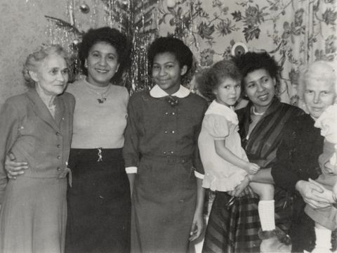 Eine altes Familienfoto mit fünf Frauen, von denen zwei kleine Kinder auf dem Arm halten, vor einem Weihnachtsbaum.