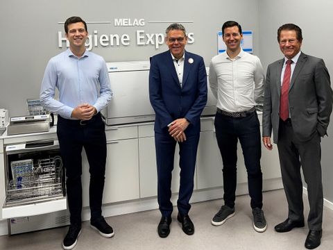 Vier Männer stehen vor einem Autoklaven und lächeln in die Kamera.