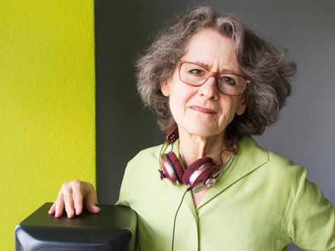 Eine Frau mit Kopfhörern legt eine Hand auf einem Lautsprecher ab.
