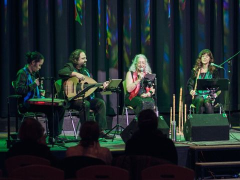 vier Menschen musizieren auf einer Bühne